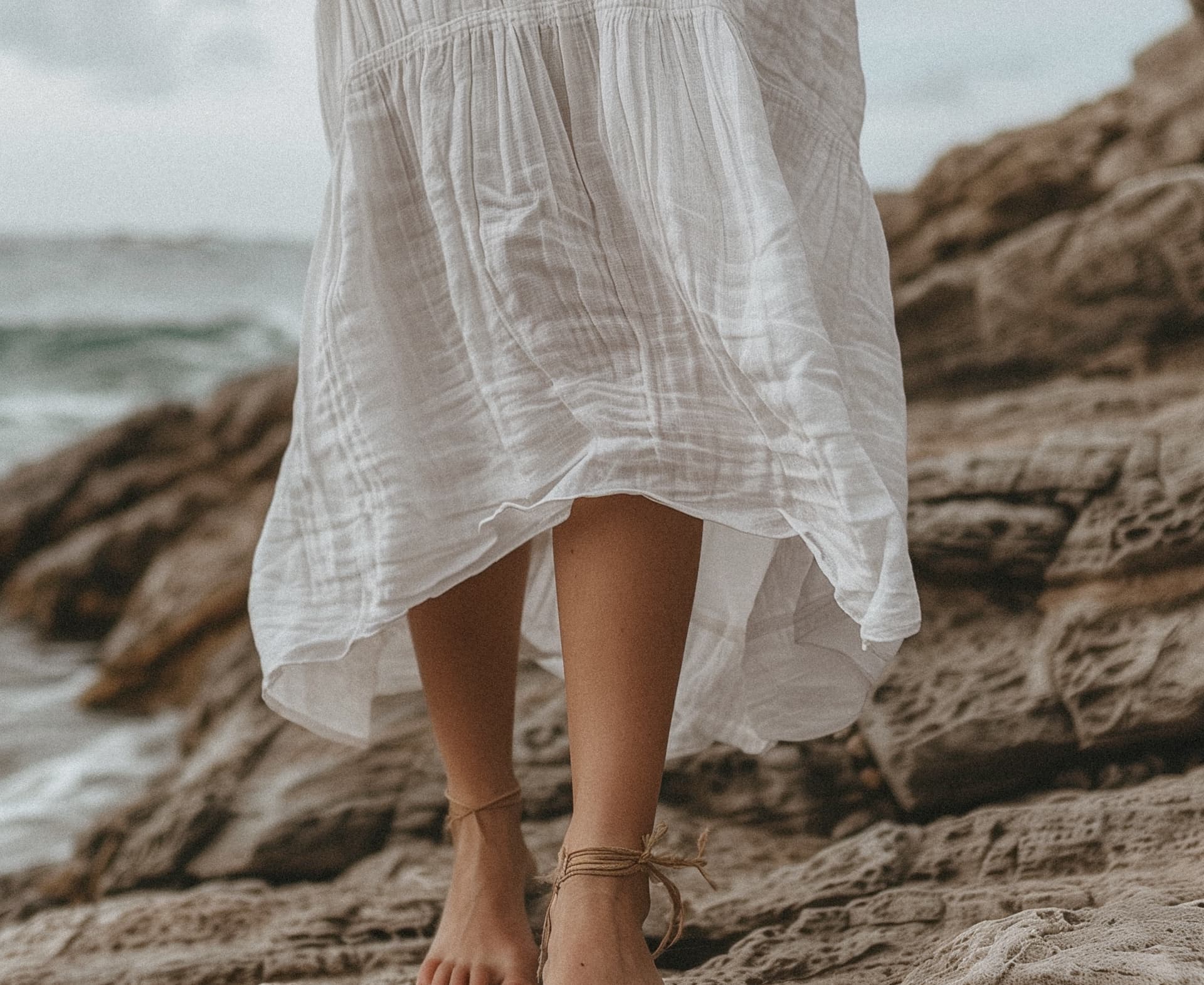 Woman in white dress on coastal rocks, freedom and confidence