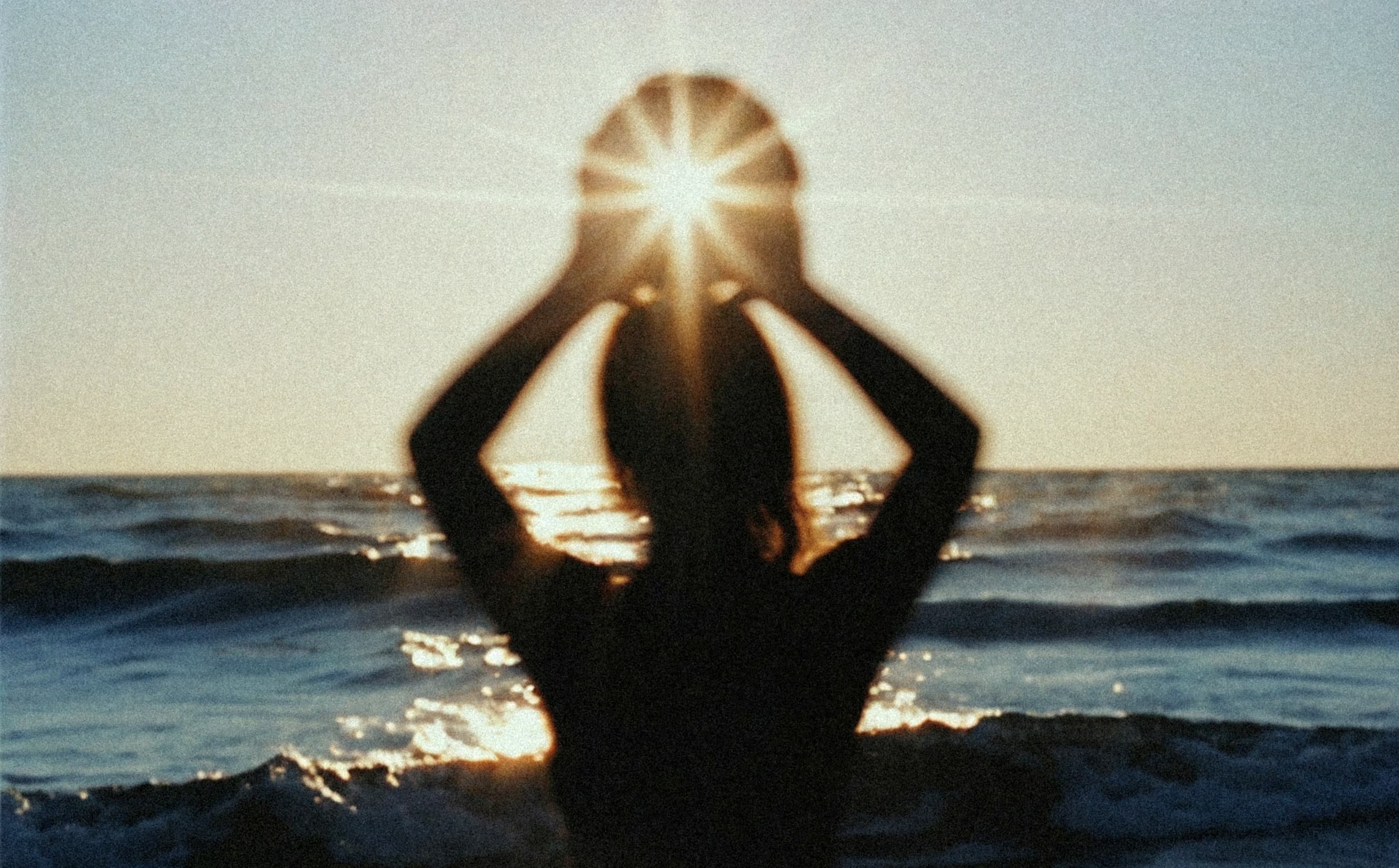 Woman silhouetted against the ocean sunset at Edmonds waterfront representing the Skin Saver Club