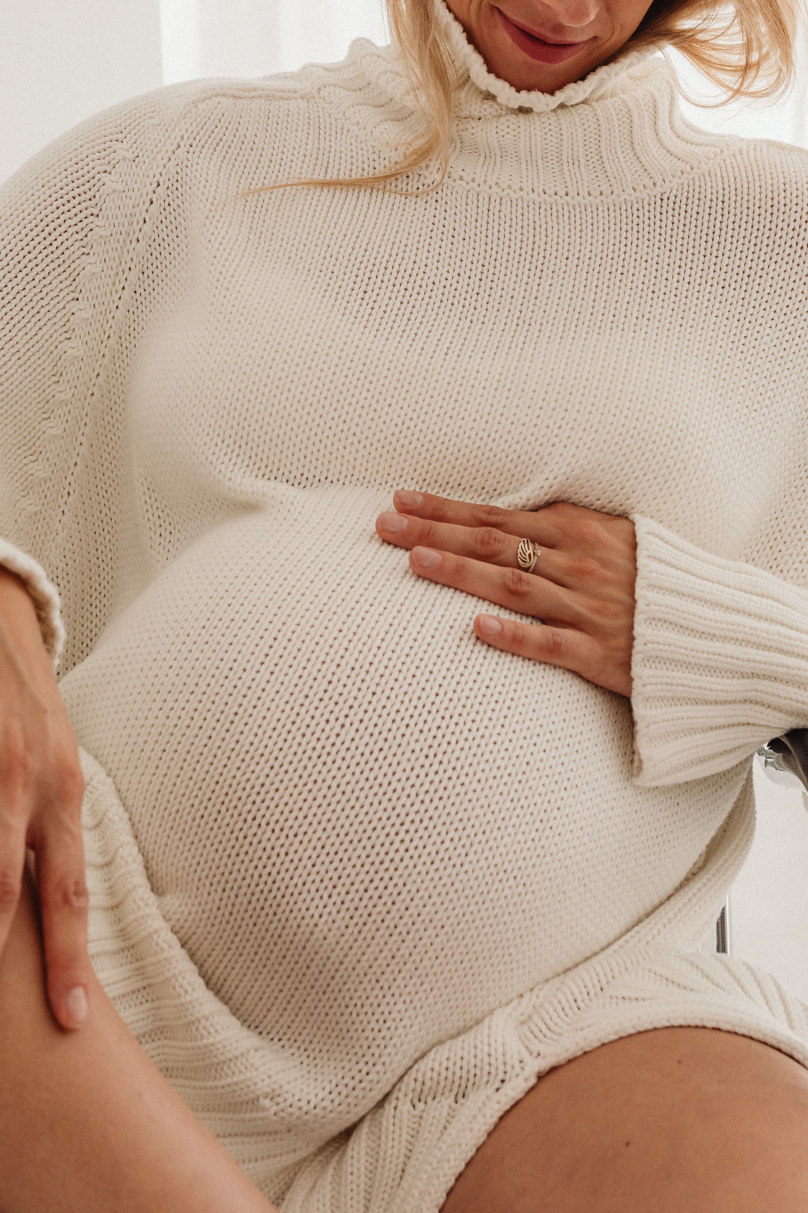 Pregnant woman in cream sweater in warm golden light