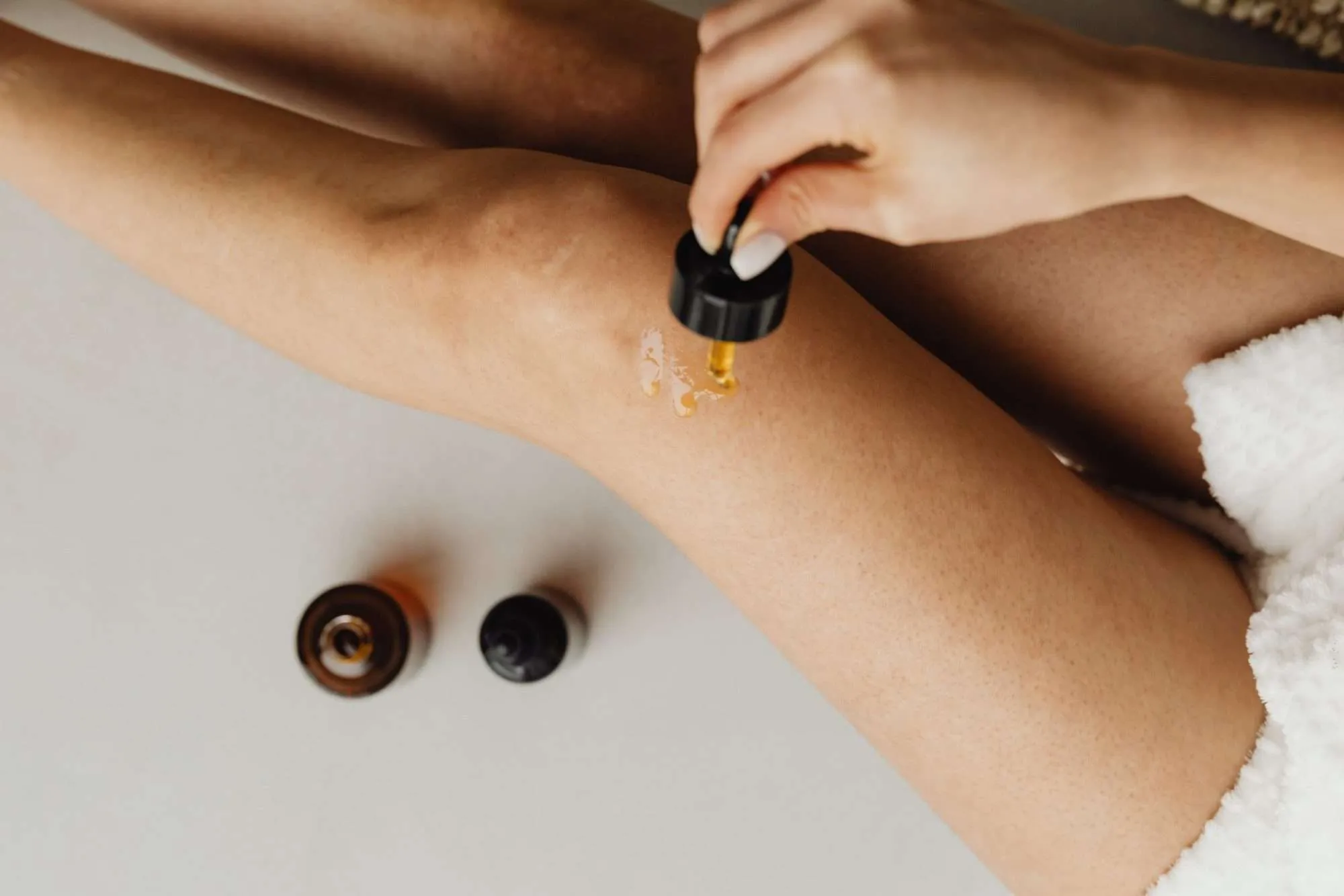 Woman applying serum to smooth skin, beginning her laser hair reduction journey