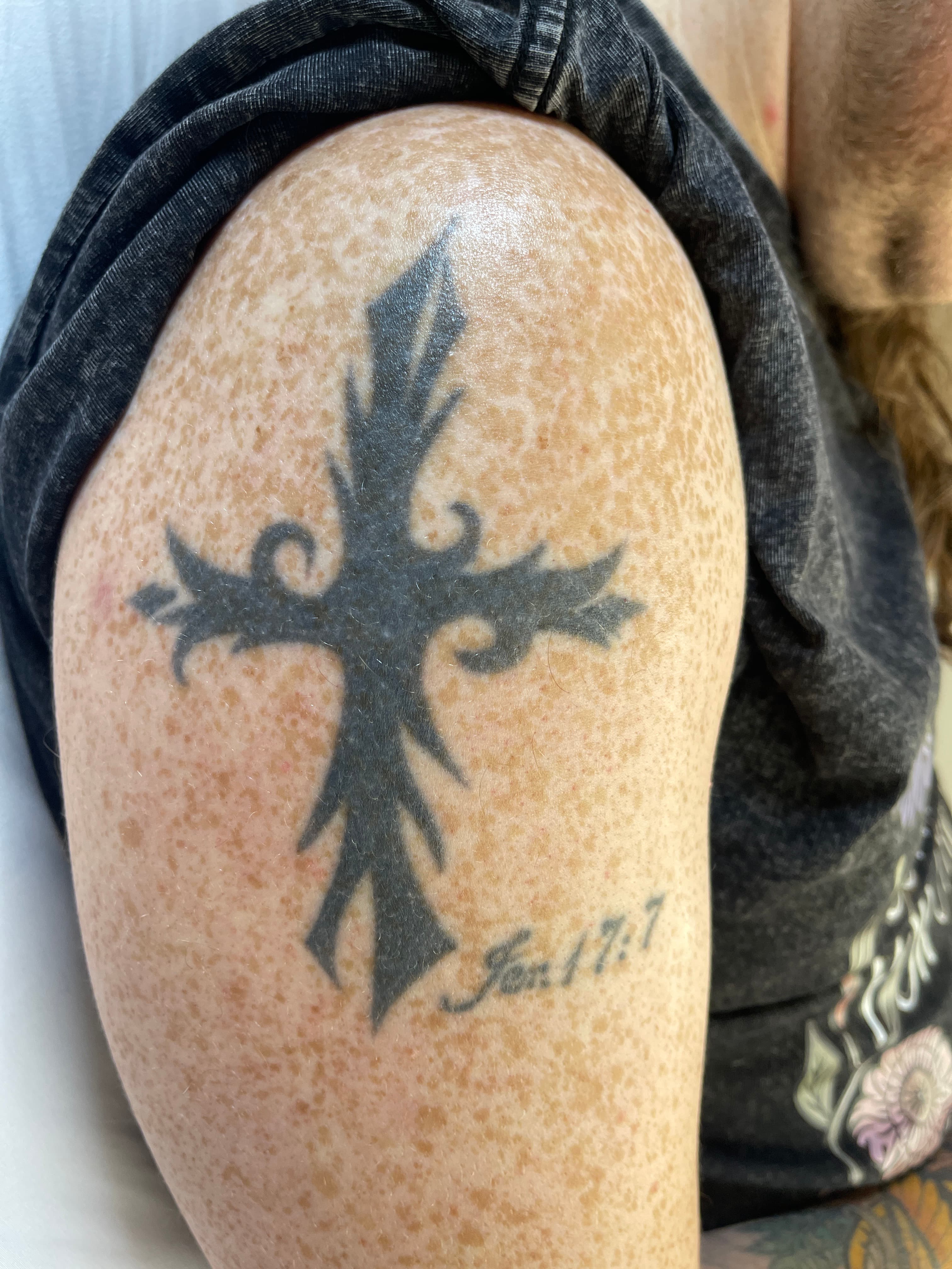 Dark tribal cross tattoo on upper arm - example of a tattoo that could benefit from pre-cover-up fading